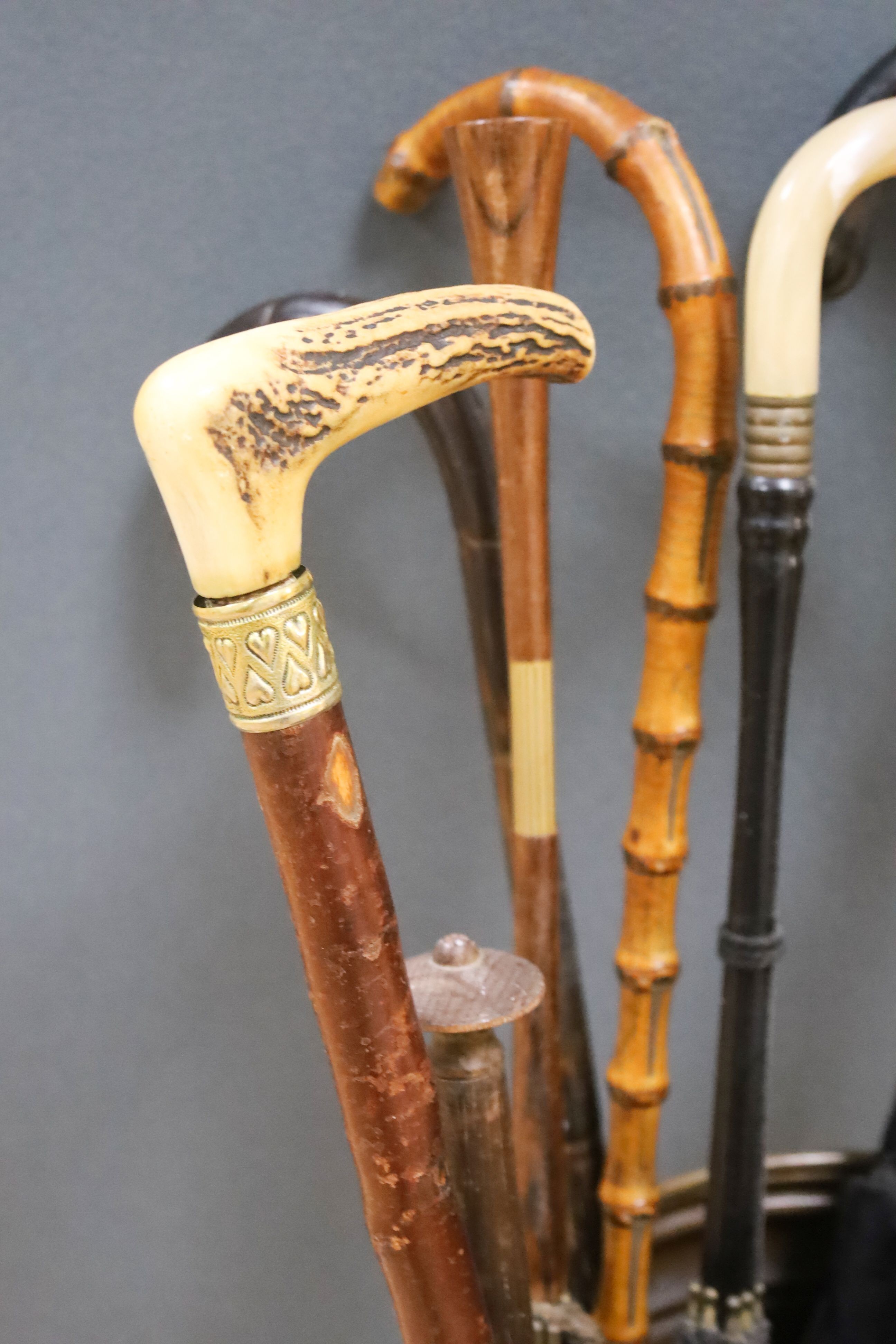 A cylindrical repousse brass stick stand, with walking sticks, parasols, etc.